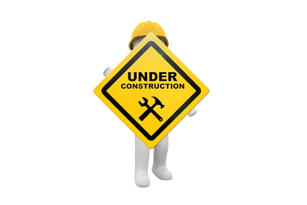 Männchen mit Bauhelm und einem Under Construction Schild in den Händen